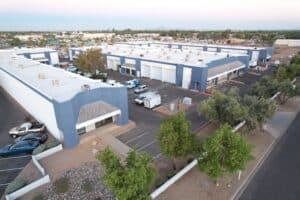 Exterior view of Key West Business Park in Gilbert, Arizona, showcasing newly painted blue and white buildings and lush landscaping with mature trees.